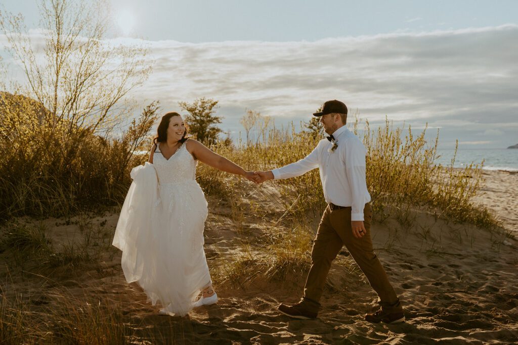 couple running in sand dunes at Michigan elopement