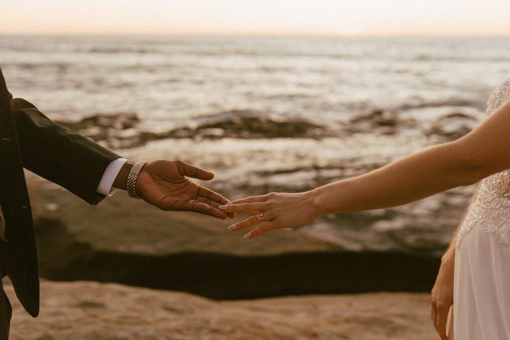 couples hold hands at sunset cliffs elopement