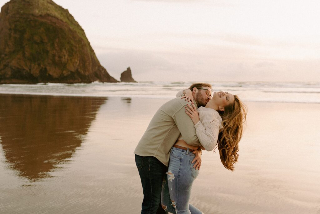 couple playfully hugging at beach engagement photoshoot