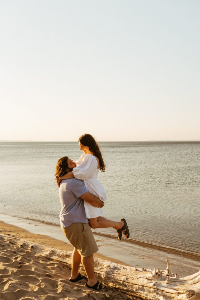 man holds up his fiance in Michigan engagement photos