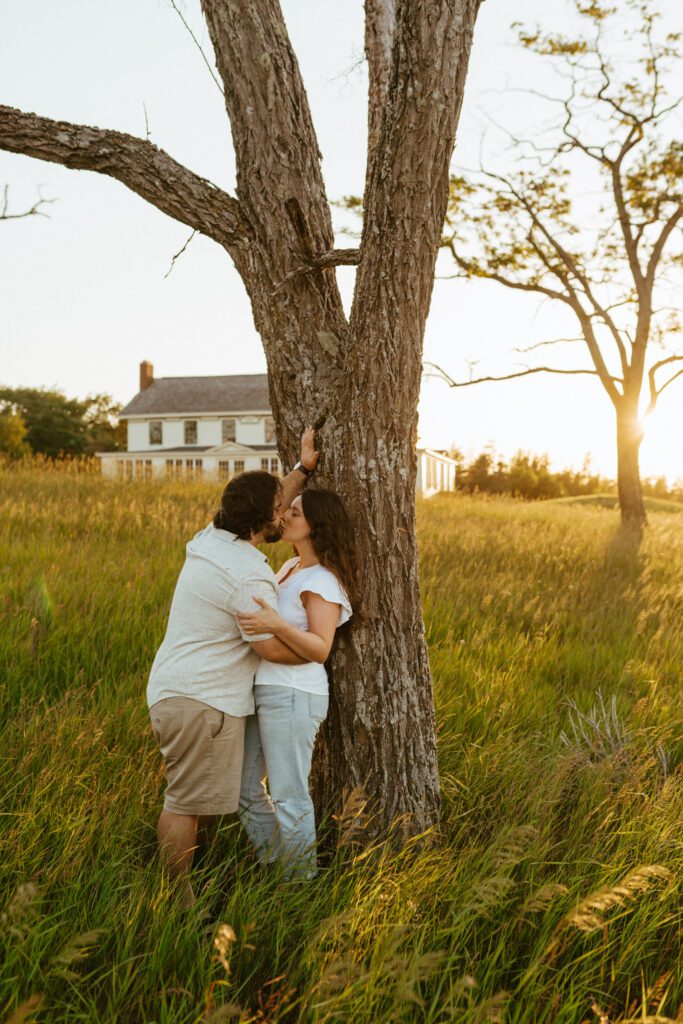 couple poses up against a tree at their sleeping bear sand dunes engagement sesion